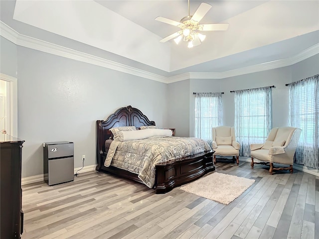 bedroom featuring a tray ceiling, light hardwood / wood-style flooring, ceiling fan, and ornamental molding