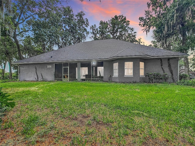 back house at dusk featuring a yard