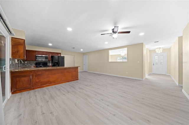 kitchen with sink, tasteful backsplash, kitchen peninsula, light hardwood / wood-style floors, and black appliances