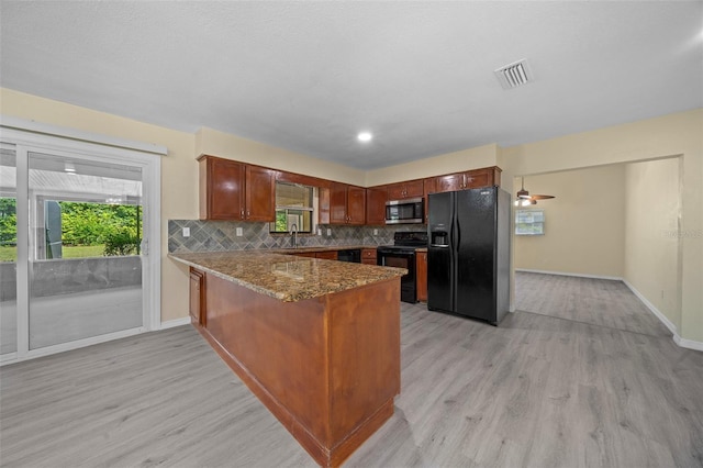 kitchen featuring black appliances, dark stone countertops, light wood-type flooring, tasteful backsplash, and kitchen peninsula