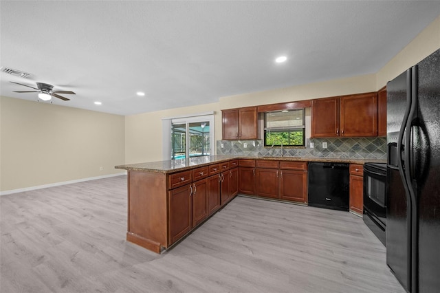 kitchen with kitchen peninsula, light wood-type flooring, sink, black appliances, and stone countertops