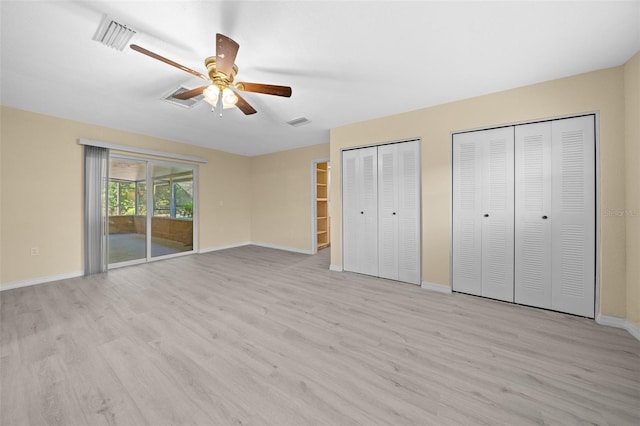 unfurnished bedroom featuring access to outside, ceiling fan, light hardwood / wood-style flooring, and two closets