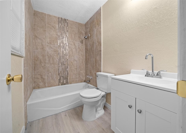 full bathroom featuring vanity, a textured ceiling, tiled shower / bath combo, wood-type flooring, and toilet