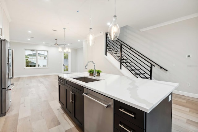 kitchen featuring stainless steel appliances, ceiling fan, sink, pendant lighting, and an island with sink