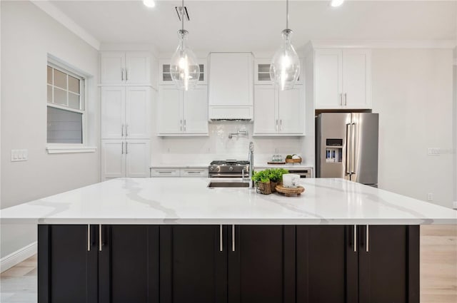 kitchen with light stone countertops, custom range hood, premium appliances, a spacious island, and white cabinets