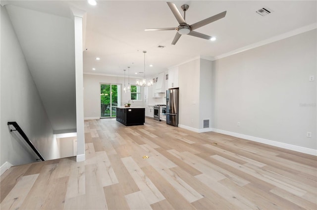 unfurnished living room featuring light hardwood / wood-style flooring, ceiling fan with notable chandelier, and ornamental molding