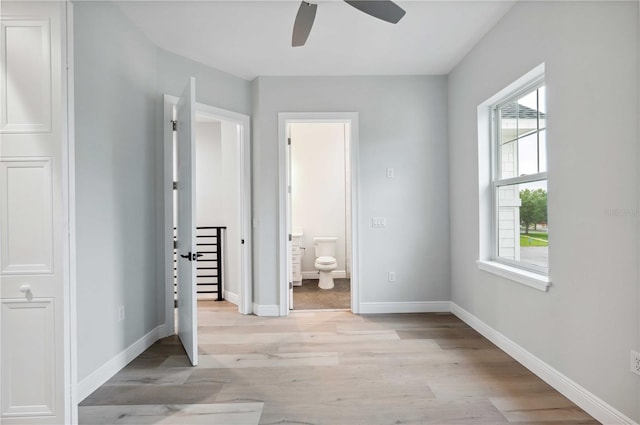 unfurnished bedroom with connected bathroom, light hardwood / wood-style flooring, and ceiling fan