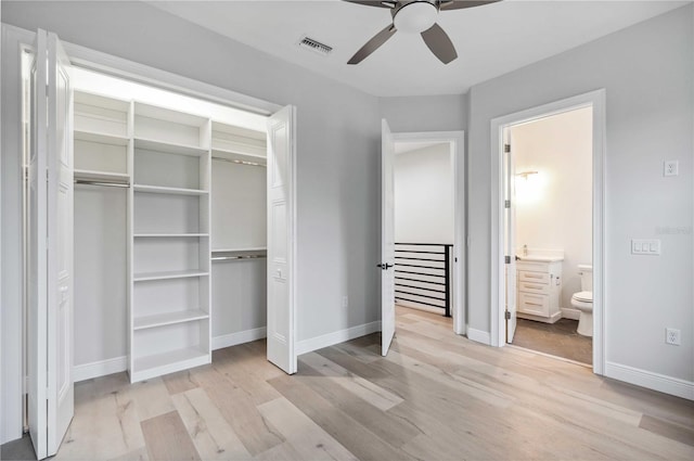 unfurnished bedroom featuring light wood-type flooring, a closet, ensuite bath, and ceiling fan