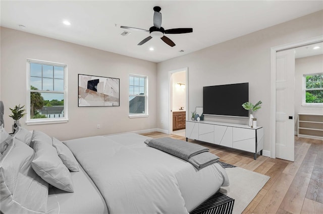 bedroom with multiple windows, ceiling fan, light hardwood / wood-style flooring, and ensuite bath