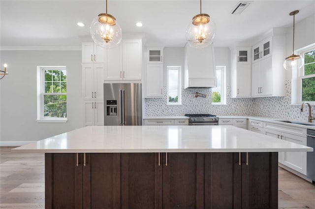 kitchen featuring custom range hood, sink, high quality appliances, a center island, and white cabinetry