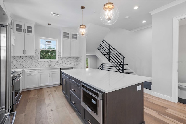 kitchen featuring backsplash, white cabinets, pendant lighting, and a kitchen island