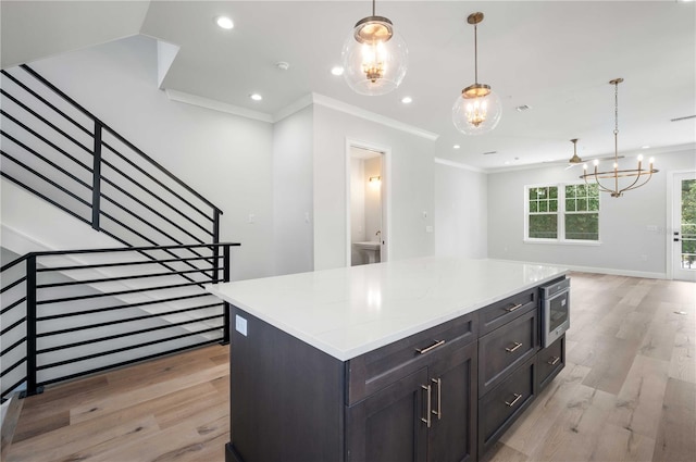 kitchen featuring light hardwood / wood-style flooring, a kitchen island, decorative light fixtures, and ornamental molding