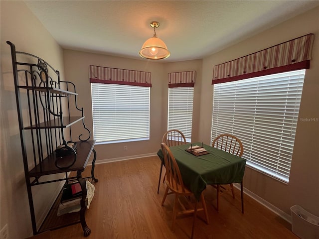 dining area with a healthy amount of sunlight, wood-type flooring, and a textured ceiling