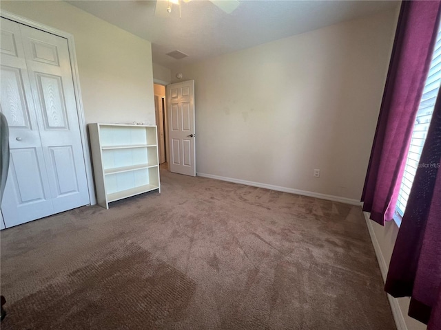 unfurnished bedroom with dark carpet, a closet, and ceiling fan