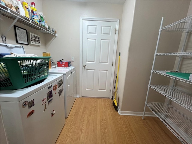 clothes washing area with separate washer and dryer and light hardwood / wood-style floors