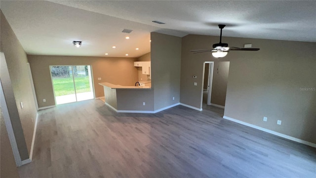 unfurnished living room featuring ceiling fan, lofted ceiling, hardwood / wood-style floors, and a textured ceiling