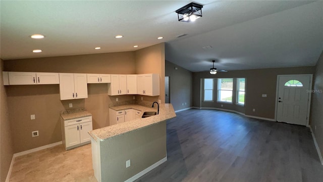 kitchen featuring white cabinetry, lofted ceiling, kitchen peninsula, and sink