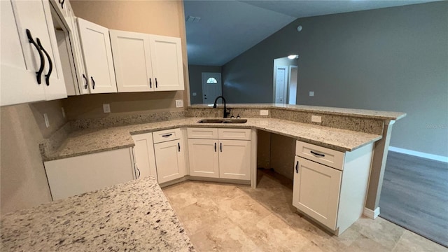 kitchen with sink, light stone countertops, kitchen peninsula, and white cabinets