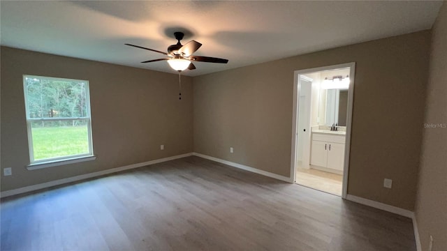 empty room with sink, wood-type flooring, and ceiling fan