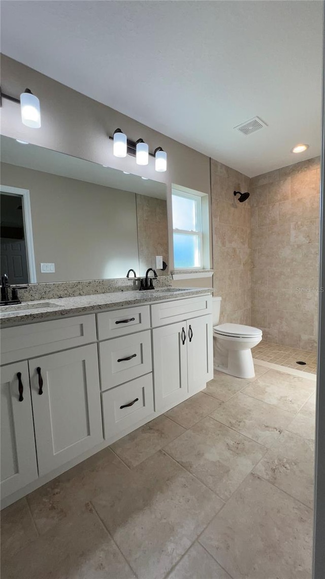 bathroom featuring vanity, tiled shower, and toilet