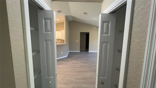 hallway with vaulted ceiling and hardwood / wood-style floors