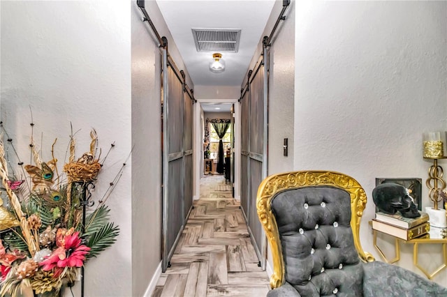 corridor featuring light parquet floors and a barn door