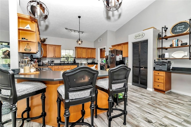 kitchen with stainless steel fridge with ice dispenser, pendant lighting, lofted ceiling, kitchen peninsula, and light hardwood / wood-style flooring