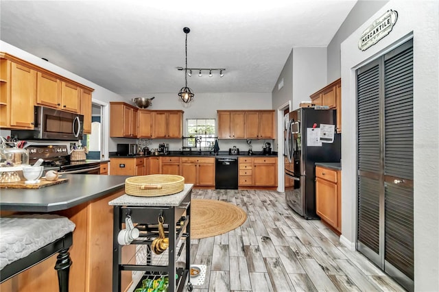 kitchen with decorative light fixtures, stainless steel appliances, a textured ceiling, and light wood-type flooring