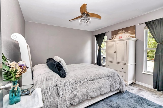 bedroom with multiple windows, ceiling fan, and light hardwood / wood-style flooring