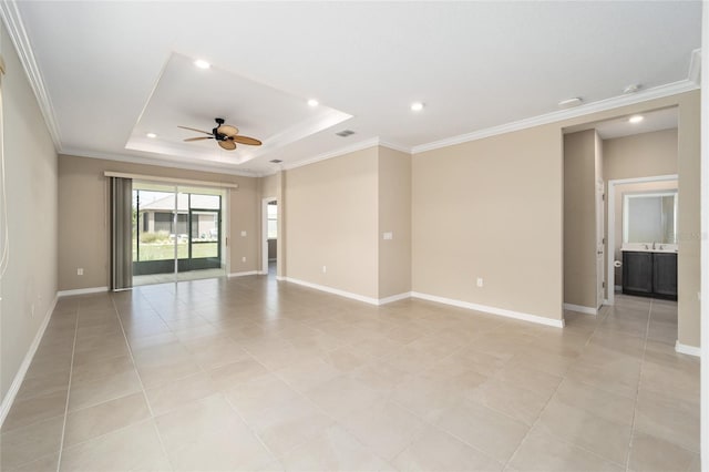 empty room with a tray ceiling, ceiling fan, and ornamental molding