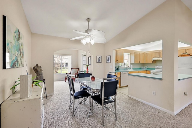 carpeted dining room featuring ceiling fan, lofted ceiling, and sink