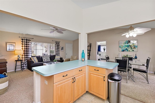 kitchen with light brown cabinets, light colored carpet, and kitchen peninsula