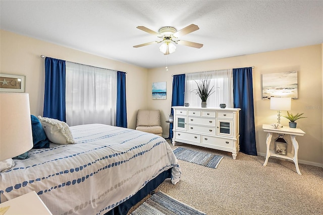 carpeted bedroom with ceiling fan and a textured ceiling