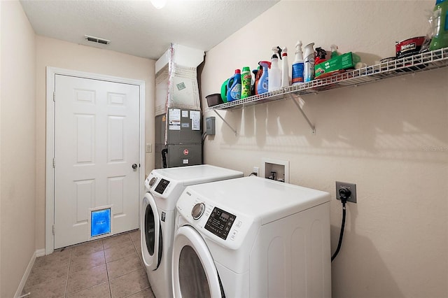 laundry room with separate washer and dryer, tile patterned flooring, and a textured ceiling