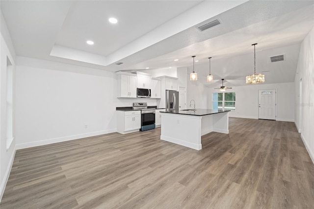 kitchen featuring ceiling fan, a center island with sink, white cabinetry, hanging light fixtures, and appliances with stainless steel finishes