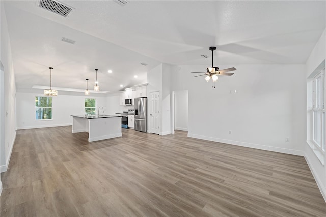 unfurnished living room with ceiling fan, sink, light wood-type flooring, and vaulted ceiling