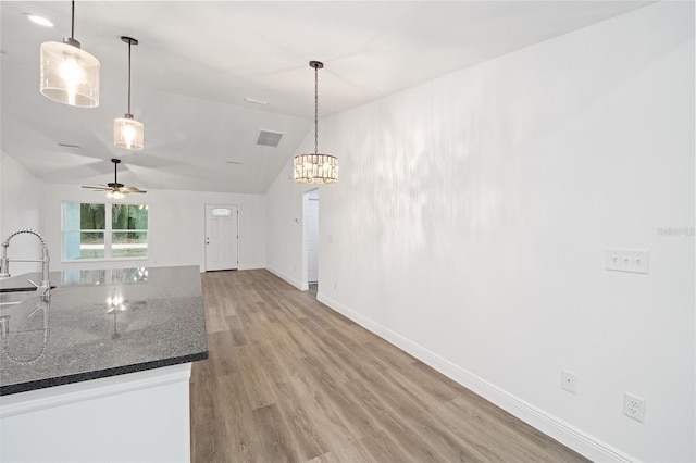 kitchen featuring lofted ceiling, sink, ceiling fan with notable chandelier, and hanging light fixtures