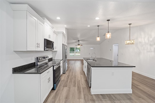 kitchen with hanging light fixtures, white cabinets, an island with sink, and stainless steel appliances