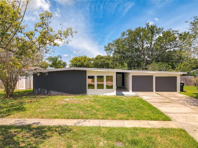 mid-century modern home featuring driveway, a garage, a front lawn, and brick siding