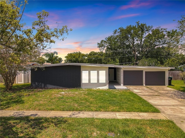 view of front facade with an attached garage, stucco siding, concrete driveway, and a yard