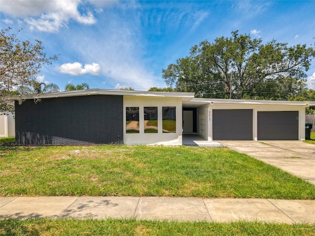 mid-century home featuring driveway, an attached garage, a front lawn, and brick siding