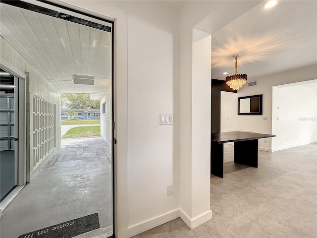 hallway with a chandelier, visible vents, and baseboards