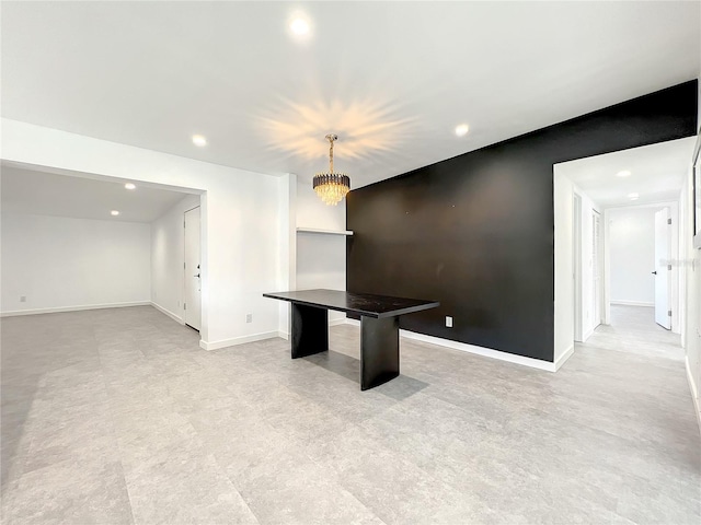 interior space with an accent wall, baseboards, a notable chandelier, and recessed lighting