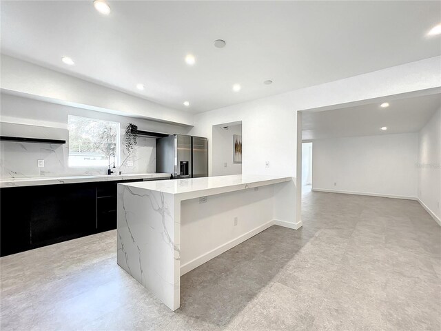 kitchen featuring dark cabinets, a kitchen island, stainless steel fridge with ice dispenser, and modern cabinets