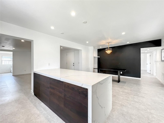 kitchen featuring baseboards, light stone counters, modern cabinets, and recessed lighting