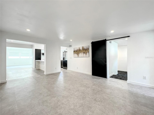 unfurnished room featuring a barn door, recessed lighting, and baseboards