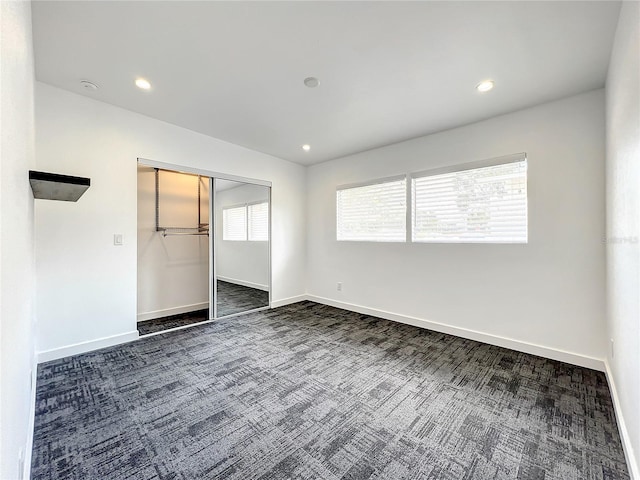 spare room with dark colored carpet, baseboards, and recessed lighting