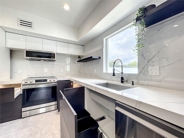 kitchen featuring visible vents, modern cabinets, stainless steel appliances, white cabinetry, and a sink