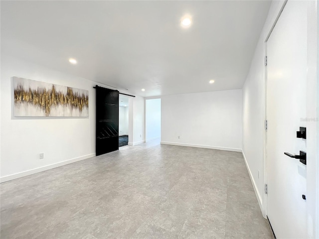 spare room featuring a barn door, baseboards, and recessed lighting