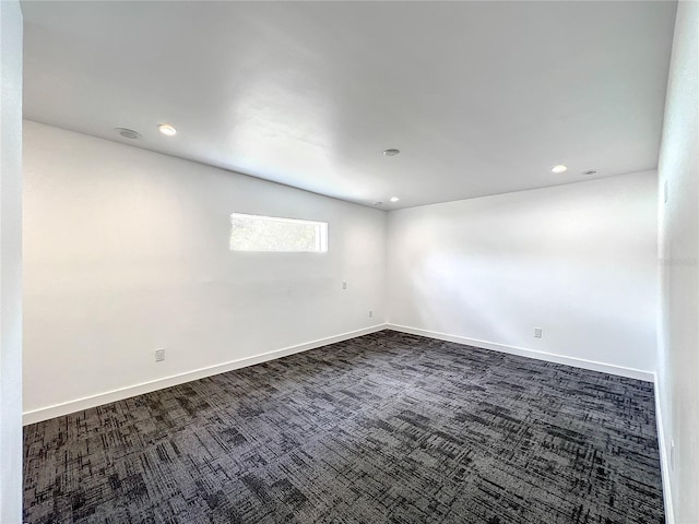 empty room featuring baseboards, dark carpet, and recessed lighting